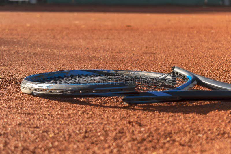 Broken tennis racket lying on a clay court symbolizing the underlying stress and fractures in professional tennis despite rising prize money